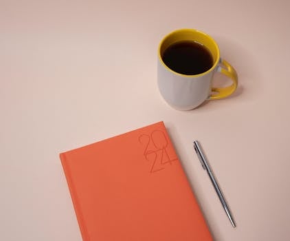 desk with a meditation journal and a steaming cup of tea